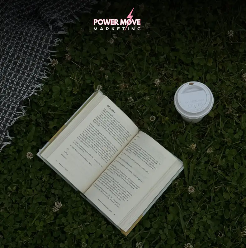 an open book and coffee cup sitting on pavement